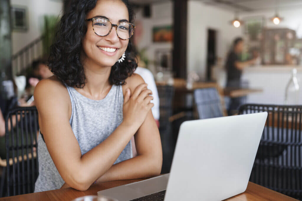 smiling woman using computer in coffee shop
